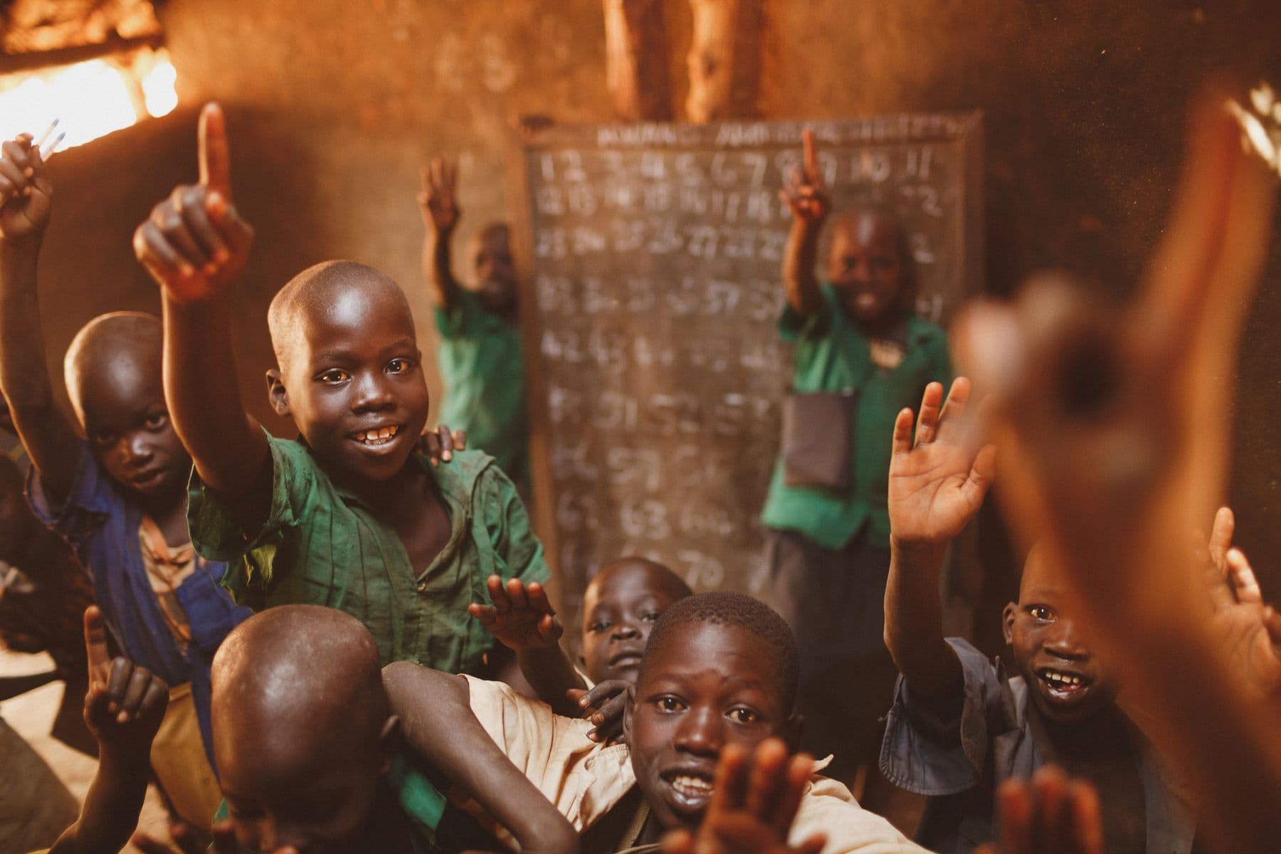 Young learners smile and raise their hands in an energetic classroom session.